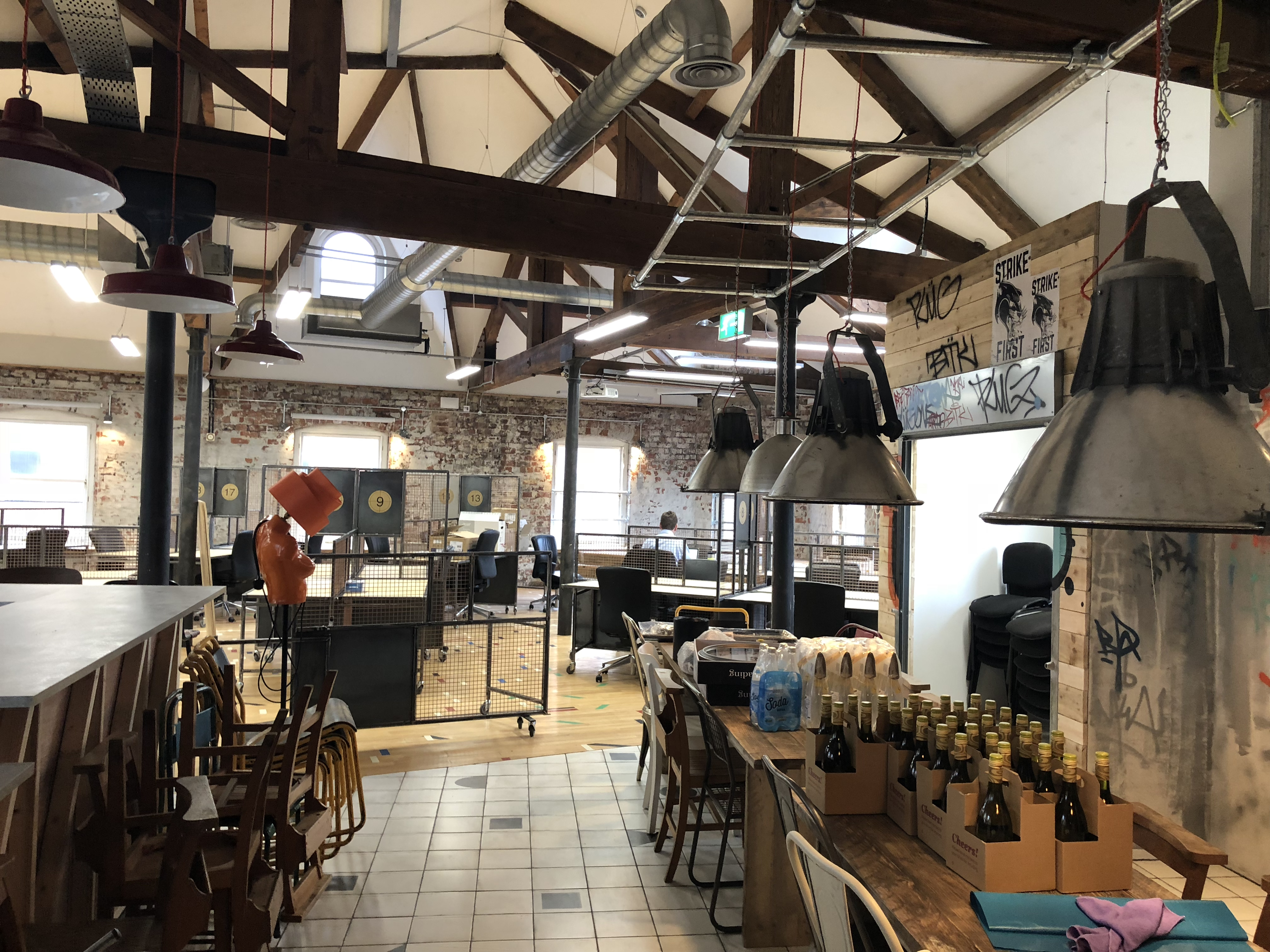 Inside New York House offices in Leeds, bar and open plan, industrial style office area with original period beams, wooden and reclaimed gym flooring and retro lighting